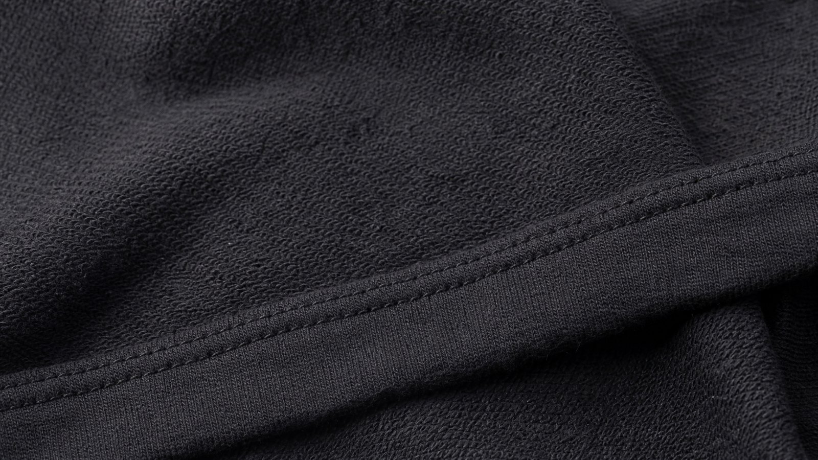 Close detail of overlapping charcoal ribbed and oatmeal cable knitted fabric