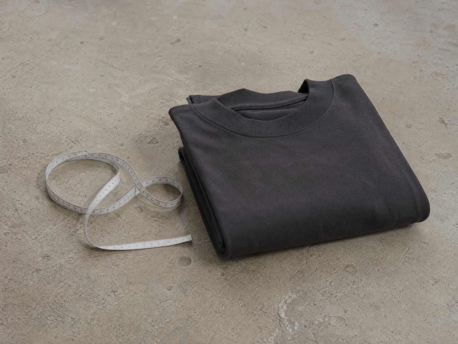 A folded ribbed knitted sock beside an uncoiled cloth tape measure